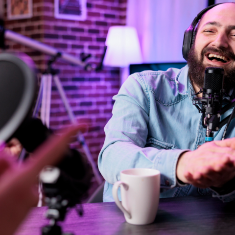 A podcaster laughing behind a studio microphone